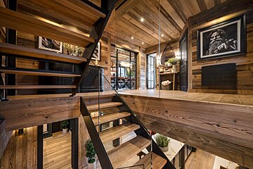 A wooden staircase with a glass railing and a picture of a man on the wall