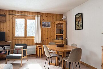 A living room with a table and chairs and a tv