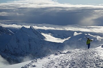a man walking with skis over his shoulder in the high mountains of Chamonix