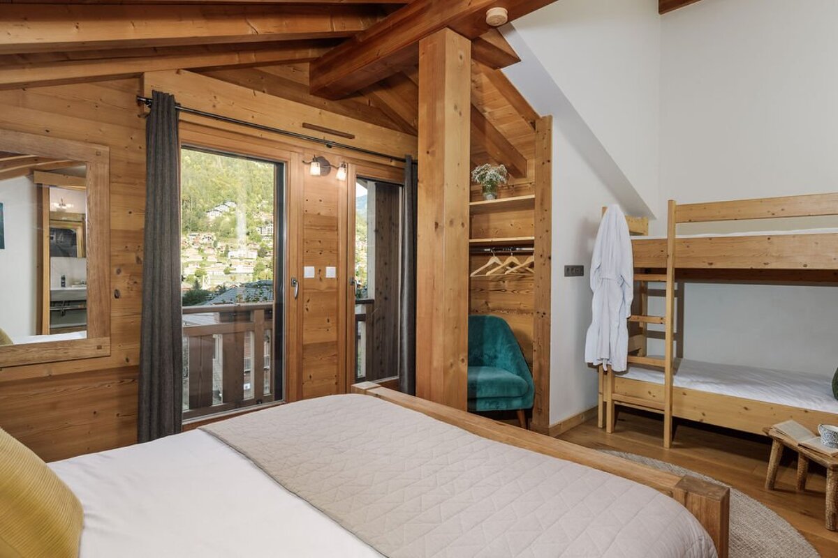 A bedroom with a bunk bed and a large window