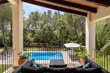A balcony overlooking a swimming pool with trees in the background