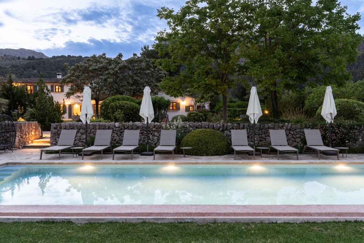 A large swimming pool surrounded by chairs and umbrellas