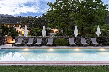 A large swimming pool surrounded by chairs and umbrellas