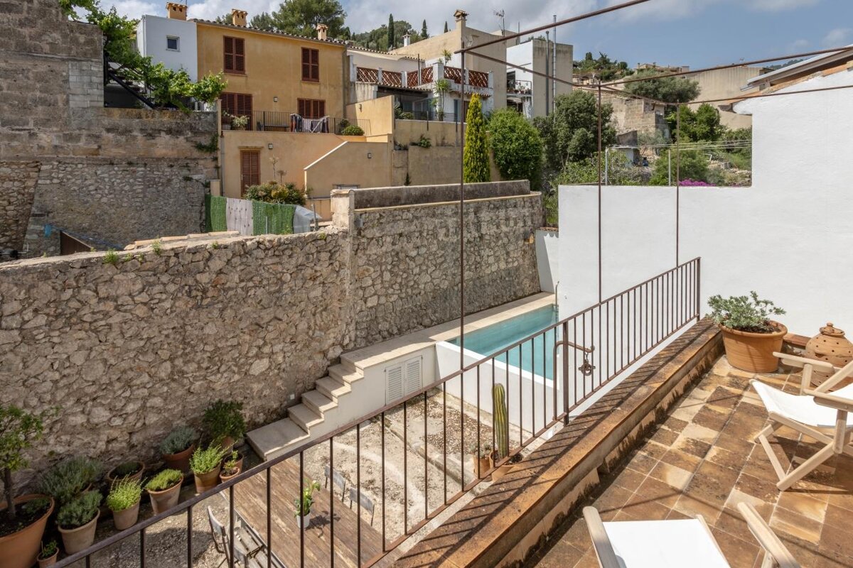 A balcony overlooking a swimming pool and a stone wall