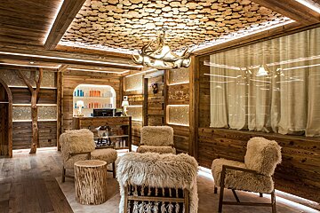 A room with a ceiling made of logs and furry chairs