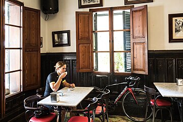 A woman sits at a table with a bicycle parked next to her