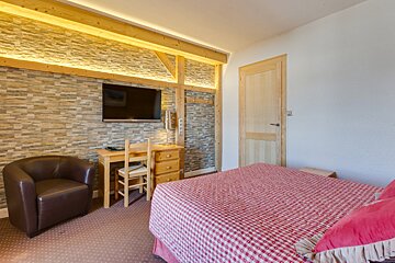 A bedroom with a bed a chair and a television