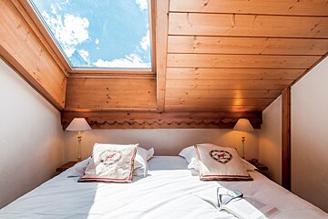 A bedroom with a skylight above the bed