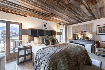 A bedroom with a wooden ceiling and a large bed