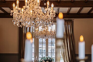 A room with a chandelier and candles in front of a window