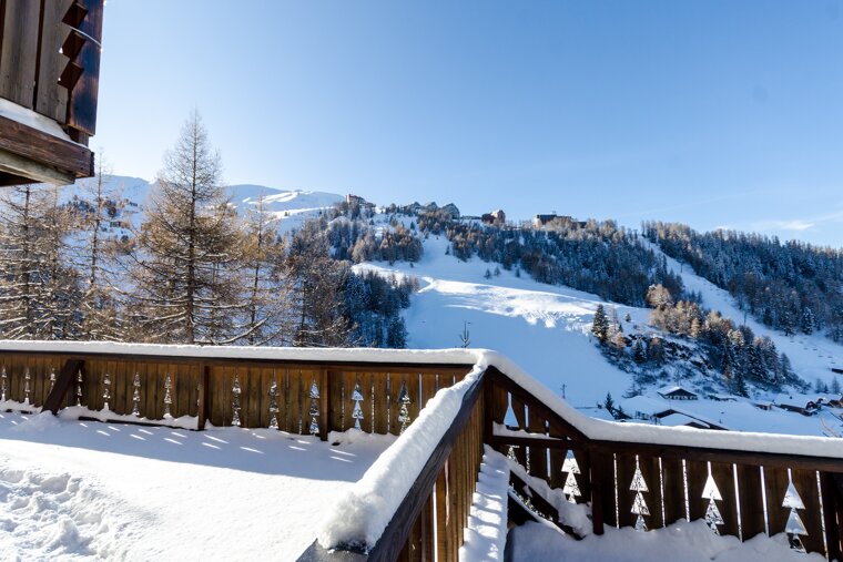 A snowy balcony with a view of a ski slope
