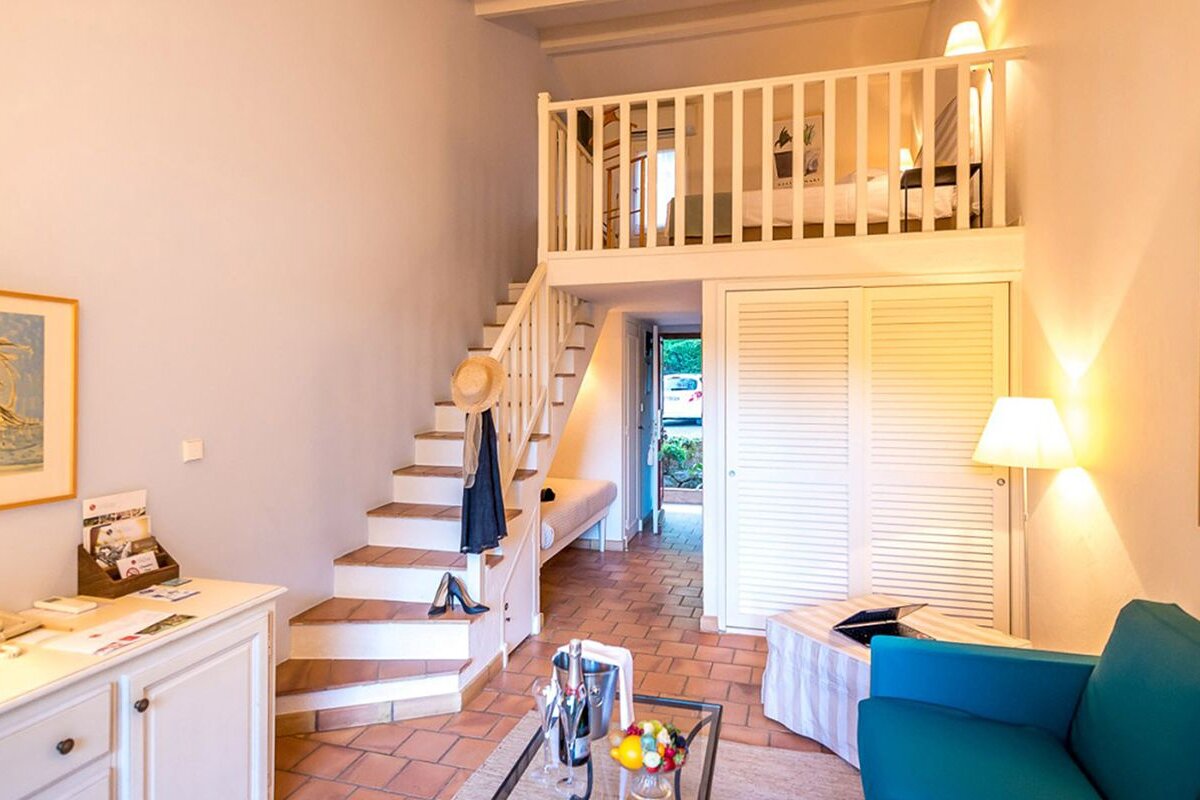 A living room with stairs leading up to a bedroom