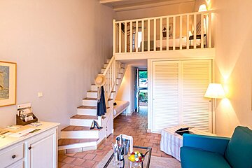 A living room with stairs leading up to a bedroom