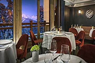 A dining room with tables and chairs and a view of the mountains