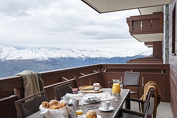 A table with a pitcher of orange juice and a basket of croissants