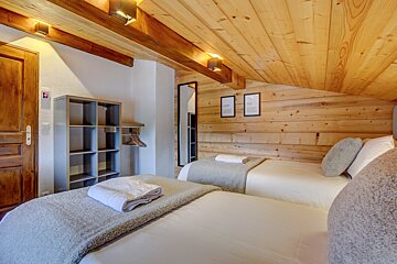 A wooden bedroom with two beds and a mirror