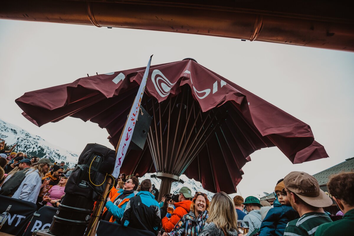 A group of people are gathered under an umbrella that says ' nt ' on it