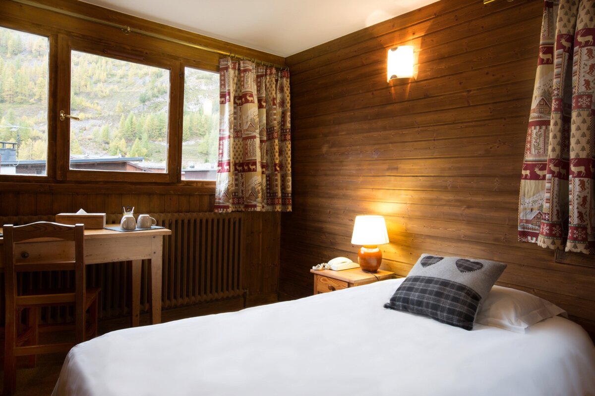 A bedroom with a bed a desk and a lamp