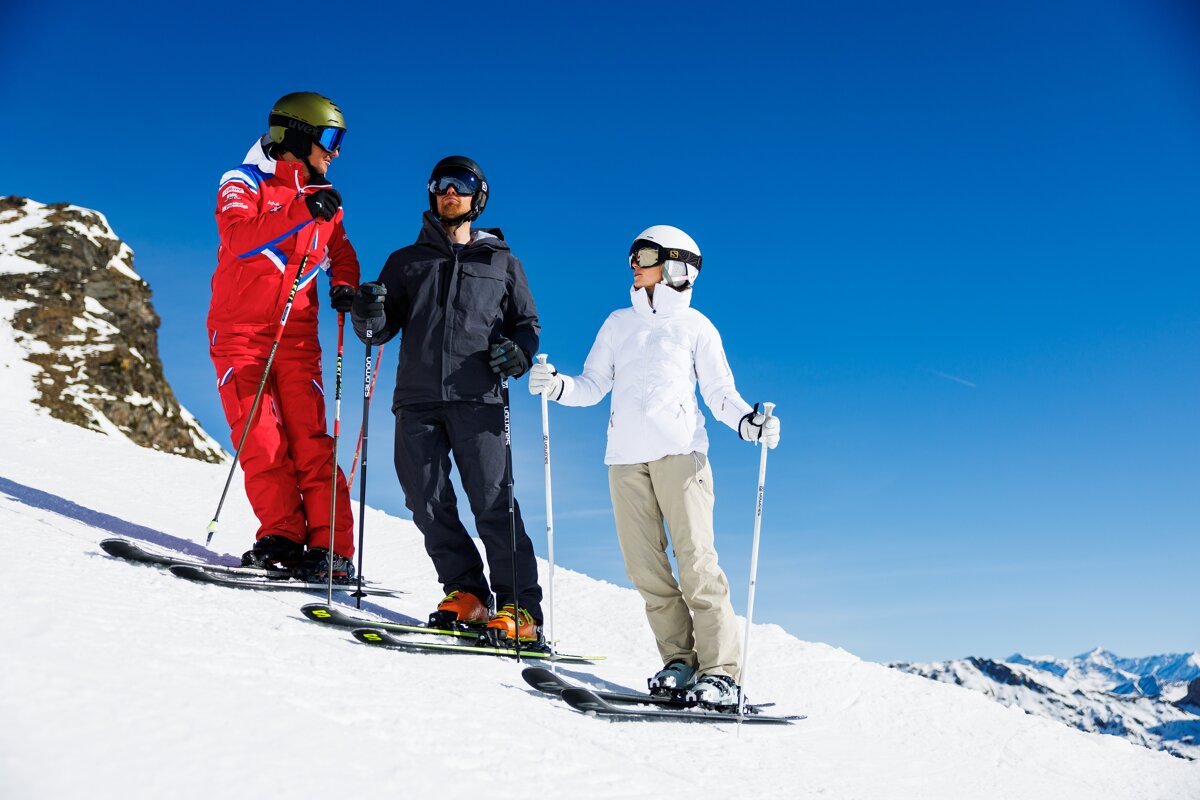 Three skiers are standing on top of a snow covered mountain