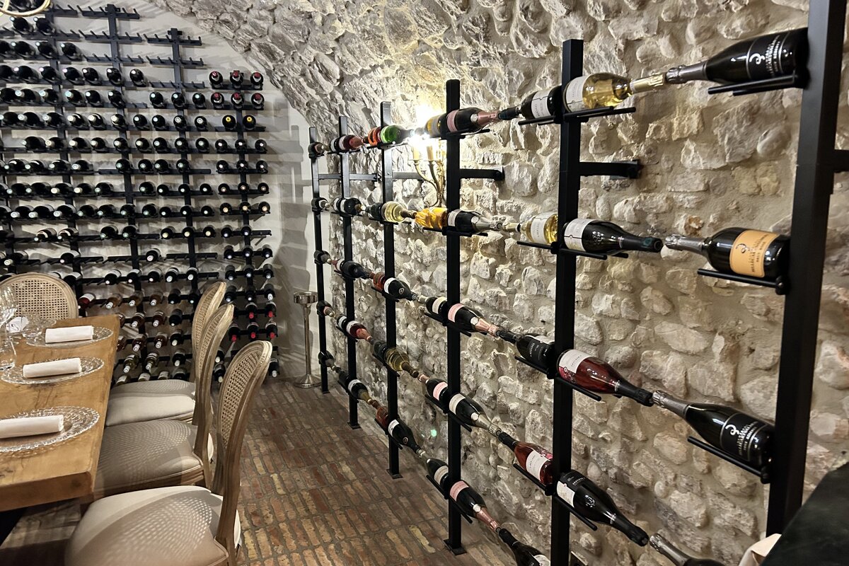 Several bottles of wine are lined up against a stone wall