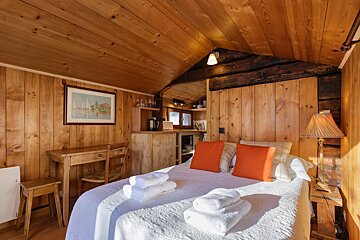 A bedroom with a bed a desk and a picture on the wall