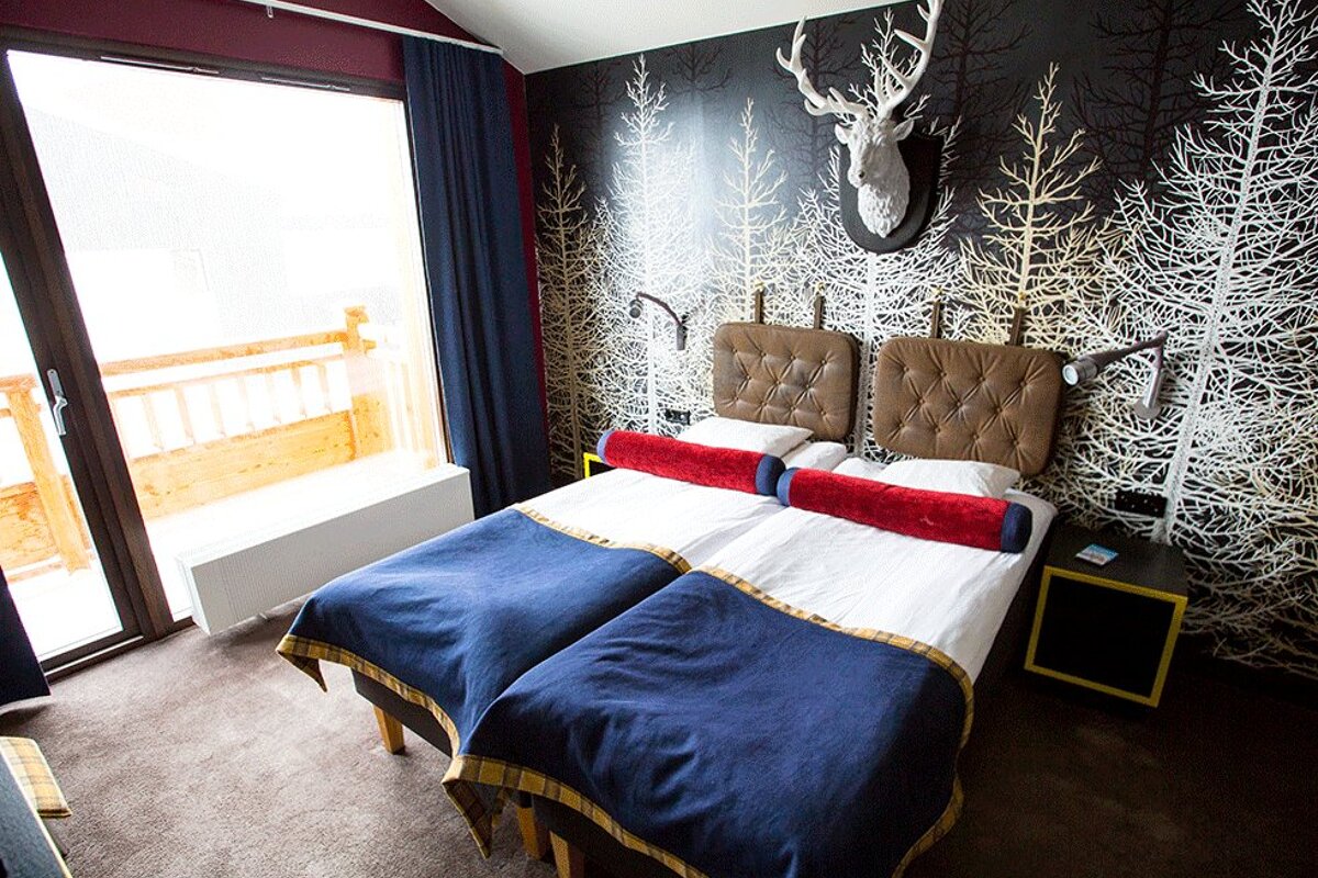 A hotel room with two beds and a deer head on the wall