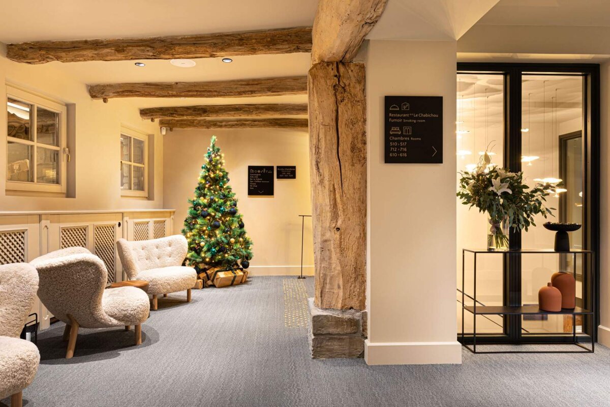 A christmas tree in a hallway next to a sign