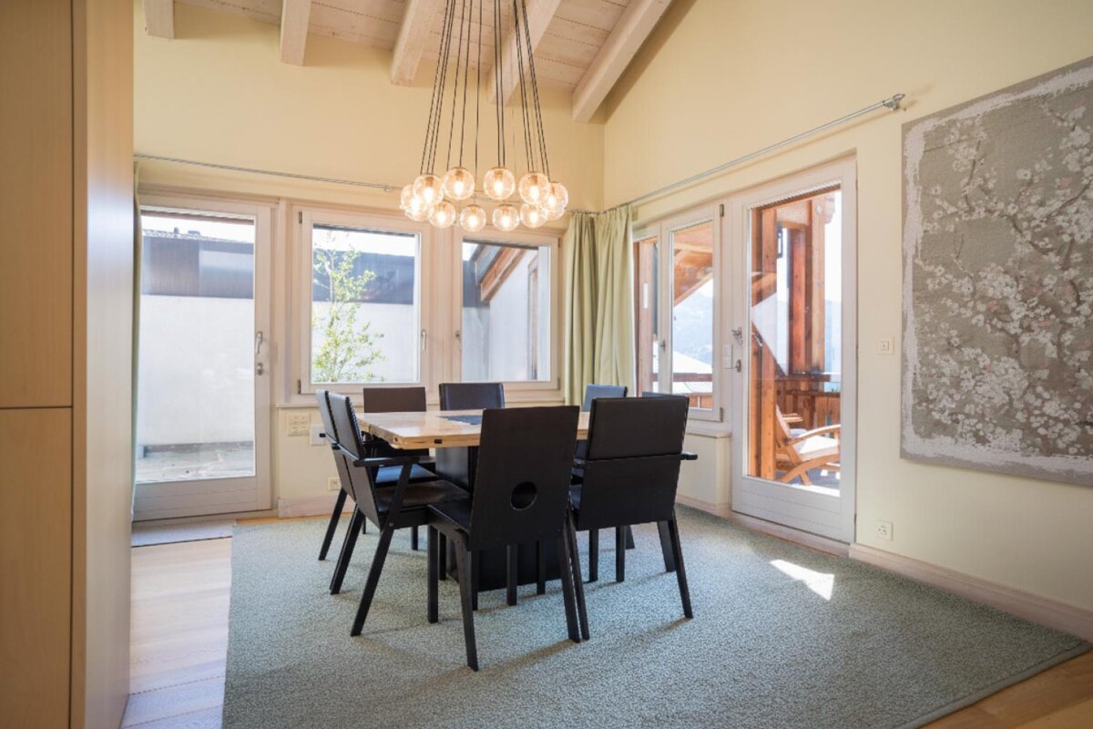 A dining room with a table and chairs and a painting on the wall