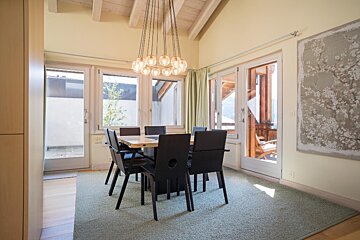 A dining room with a table and chairs and a painting on the wall