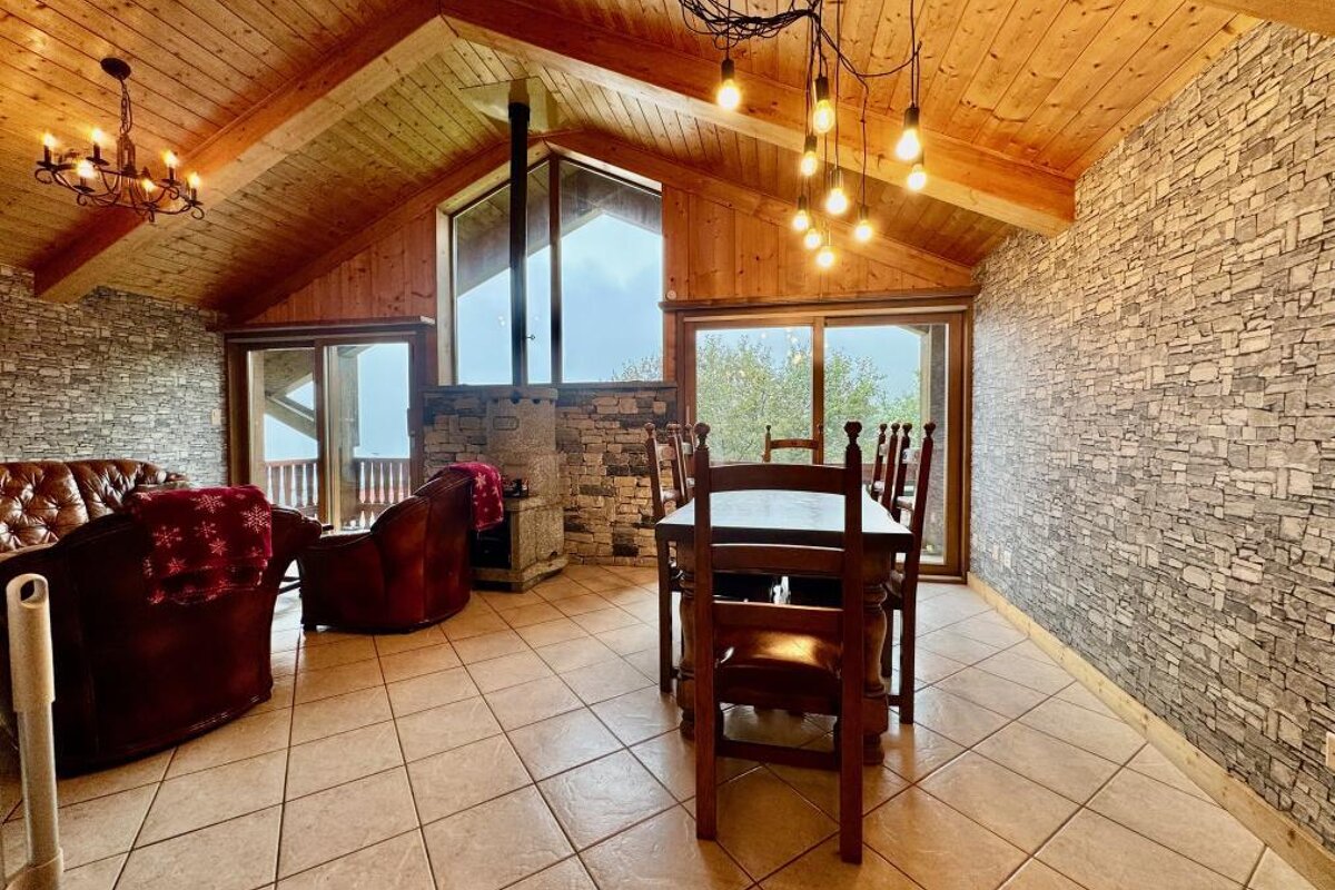 A living room with a vaulted ceiling and a table and chairs