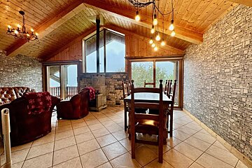 A living room with a vaulted ceiling and a table and chairs