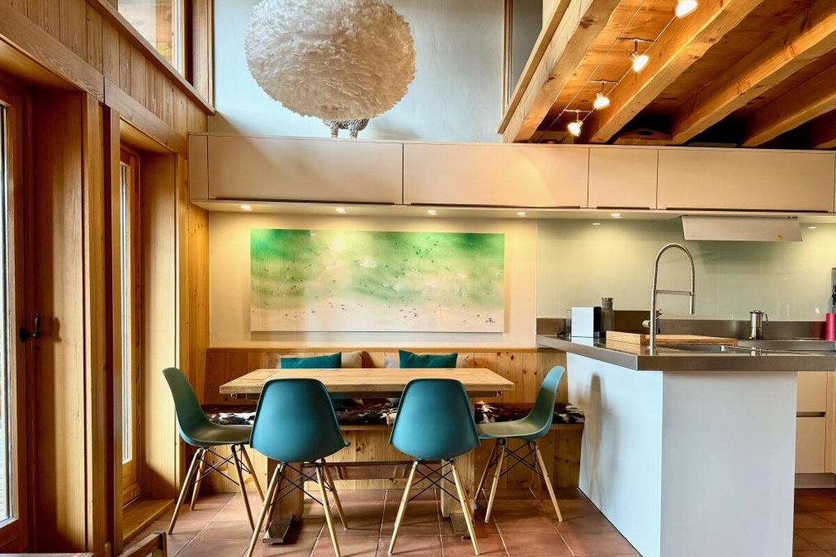 A kitchen with a table and chairs and a painting on the wall