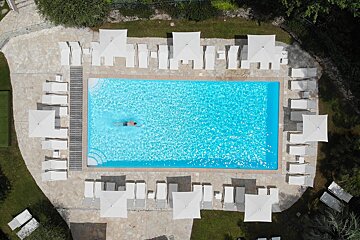 An aerial view of a large swimming pool surrounded by chairs and umbrellas