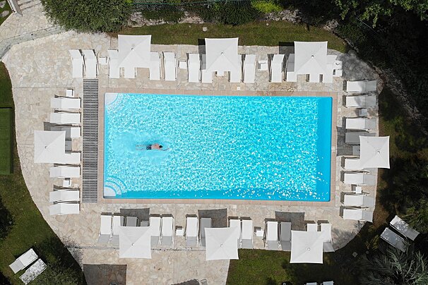 An aerial view of a large swimming pool surrounded by chairs and umbrellas