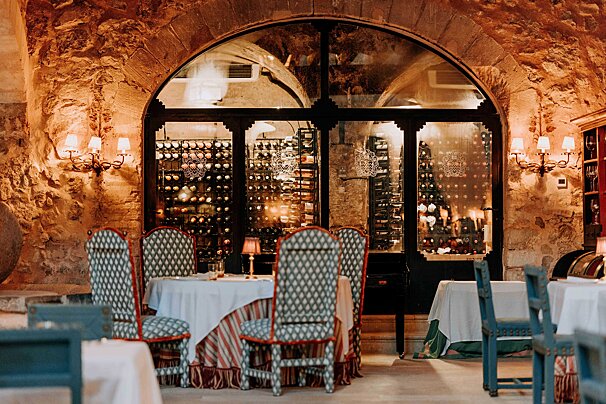 A restaurant with tables and chairs in front of a wine cellar