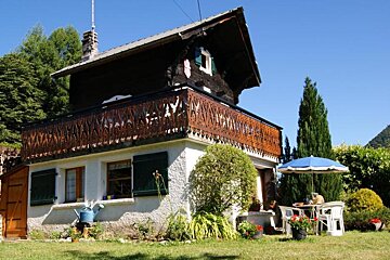 A small house with a balcony and umbrella in front of it