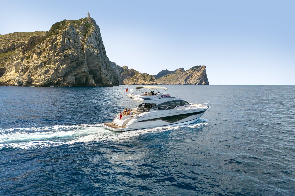 Two boats are floating in the ocean with a lighthouse in the background