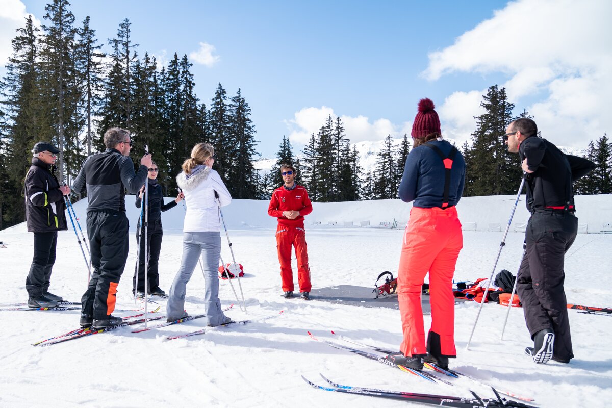 A group of people standing in the snow with skis and poles