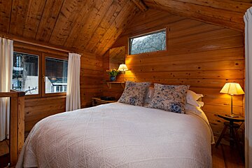 A bedroom in a log cabin with a bed and two lamps