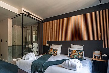 A hotel room with a bed and a walk in shower