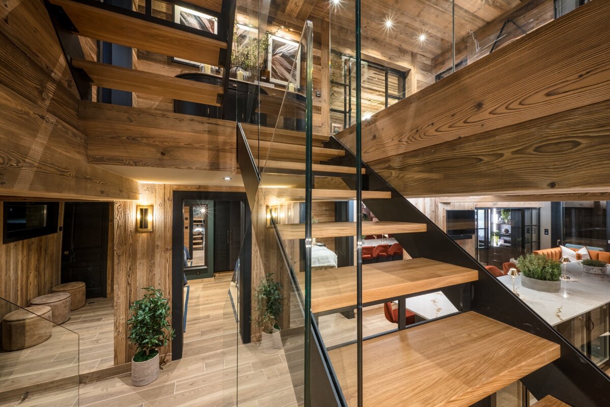 A wooden staircase with a glass railing in a house