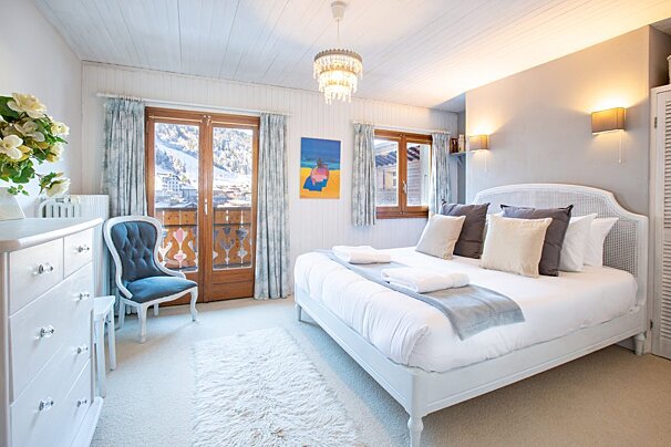 A bedroom with a large bed and a blue chair