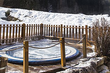 A hot tub surrounded by snow and a wooden fence