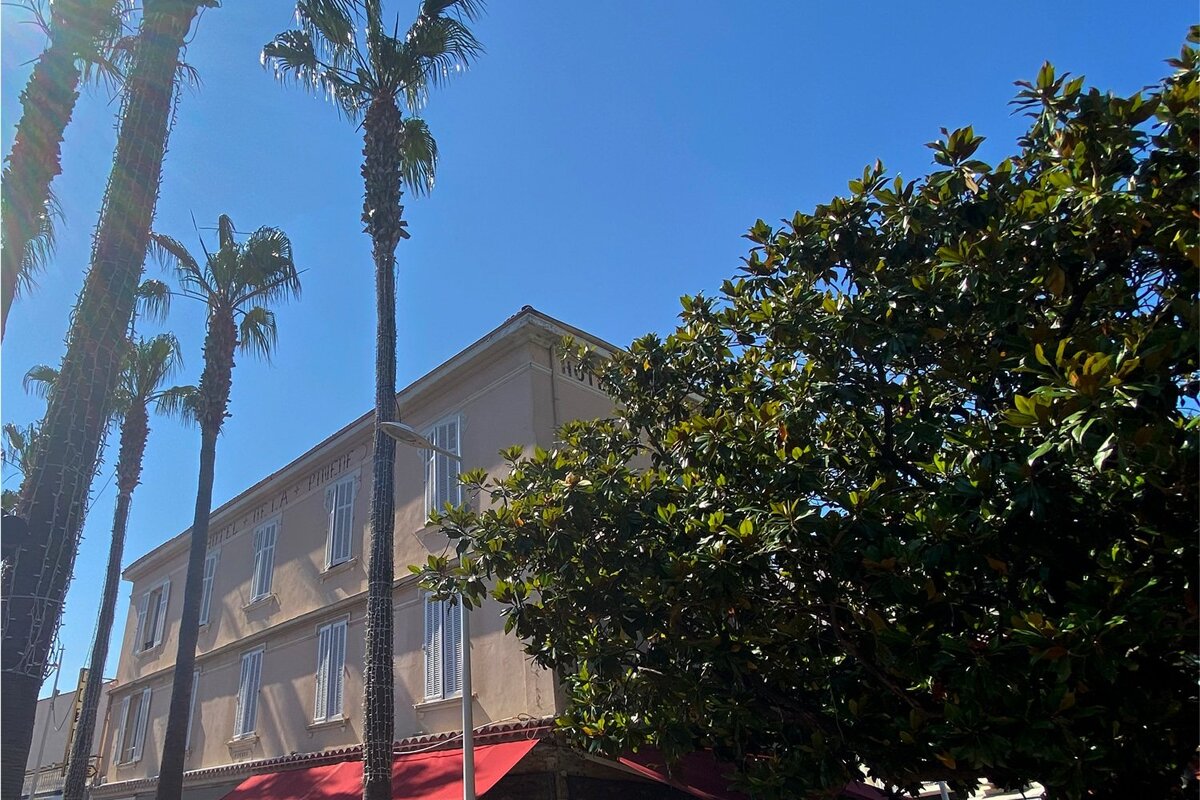 A building with a red awning and palm trees in front of it