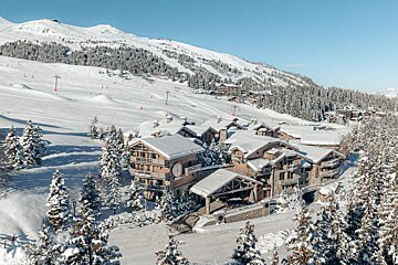 A snowy landscape with a ski resort in the background