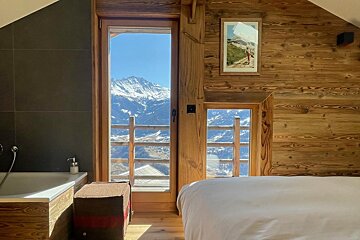 A bedroom with a view of the mountains and a bathtub