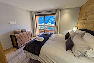 A bedroom with a large bed and a dresser