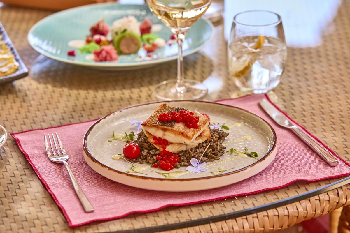 A plate of food on a table next to a glass of wine