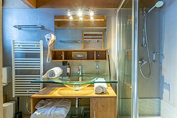 A bathroom with a glass sink and a shower
