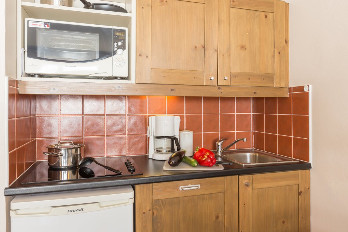A small kitchen with a brandt refrigerator and a microwave